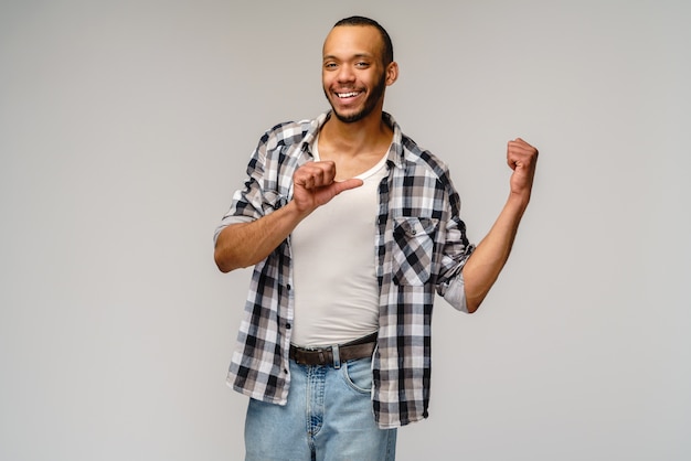 Alegre amigável jovem afro-americano iwearing camisa casual, apontando com o dedo no espaço da cópia.