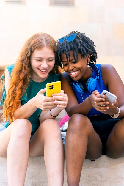 Alegre amistad multirracial mujeres jóvenes riendo y abrazando al aire libre