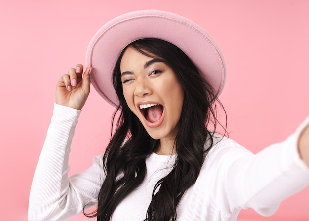 Alegre bastante joven mujer asiática tomando un selfie estando aislado, con sombrero