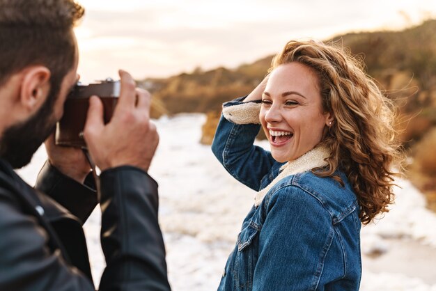 Alegre bastante joven posando delante de su novio que la toma en la playa.