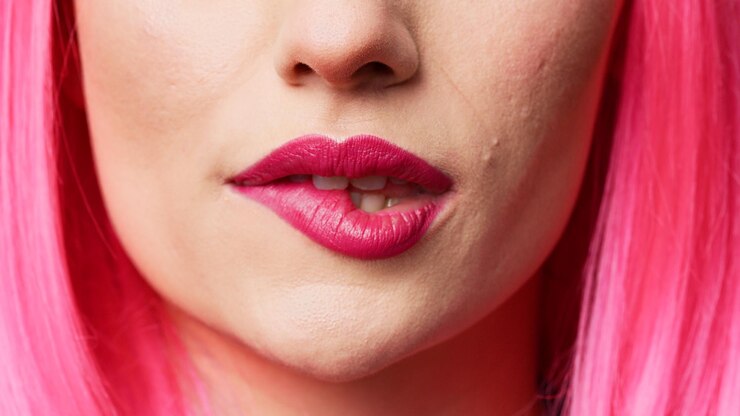 Foto alegre bonita adulta com batom rosa mordendo os lábios no estúdio, sentindo-se sensual e atraente. garota confiante e despreocupada com boca bonita agindo sedutora e gostosa. close up extremo, tiro macro.