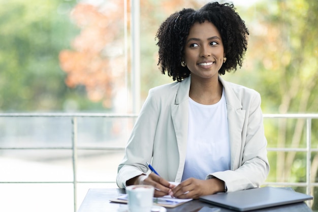 Alegre y bonita mujer negra contratista independiente trabajando en un café