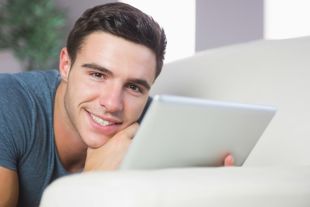 Alegre, bonito, homem, deitado, sofá, usando, tabuleta