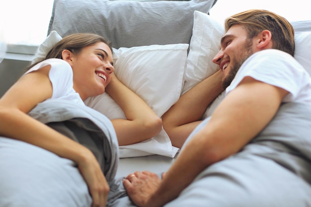 Alegre casal acordando e olhando um ao outro na cama