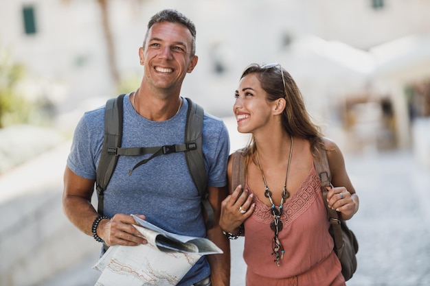 Alegre casal apaixonado se divertindo e aproveitando as férias de verão enquanto caminhava e explorava uma cidade mediterrânea.