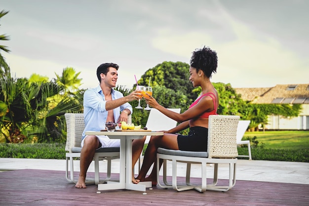 Alegre casal de férias tomando café da manhã sentado no terraço recém-casados torradas coquetéis