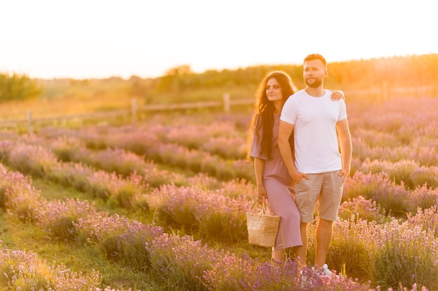 Alegre casal elegante dançando no campo de lavanda sorrindo tendo um encontro romântico no pôr do sol