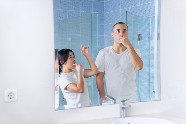 Alegre casal escovando os dentes no banheiro