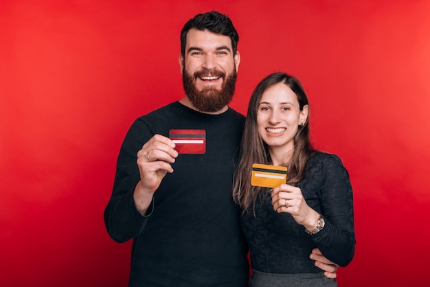 Alegre casal jovem sorridente, mostrando cartões de crédito