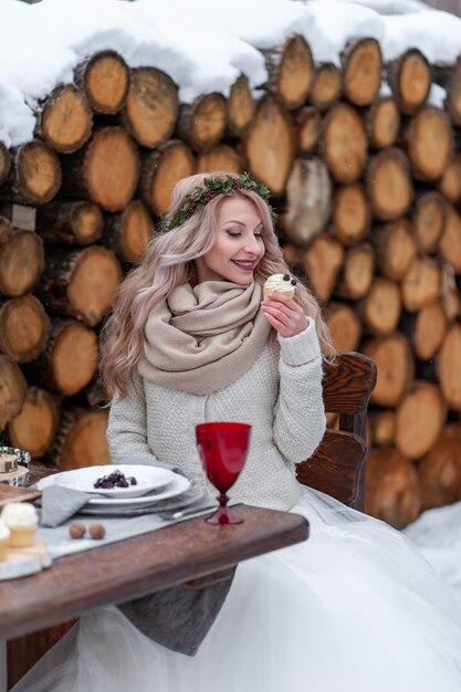 Alegre chica rubia con el pelo rizado sostenga una magdalena. Enfoque selectivo en el cupcake.