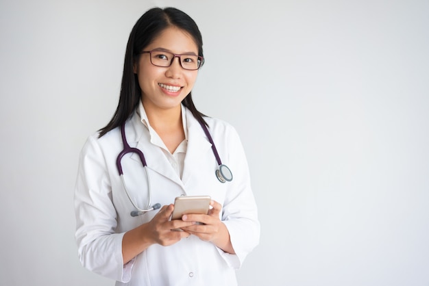 Alegre confiante médico usando smartphone