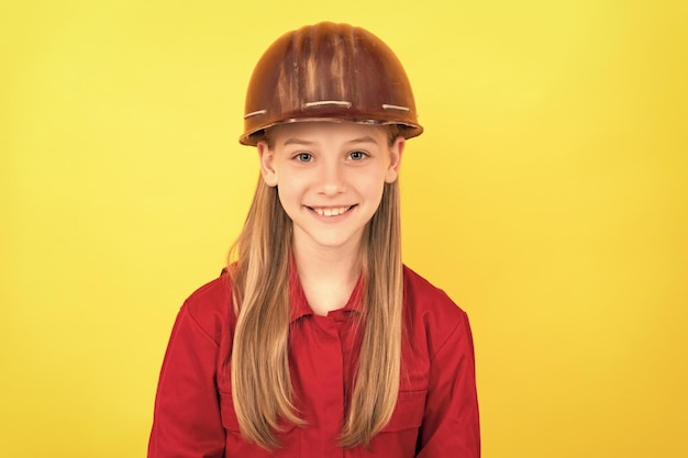 Alegre criança adolescente no capacete do construtor em fundo amarelo