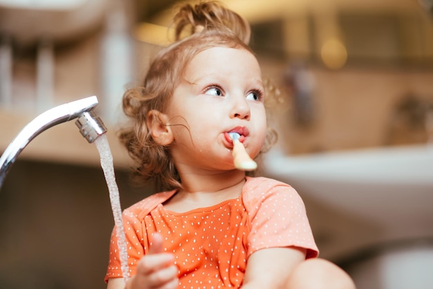 Alegre criança feliz escova os dentes de manhã no banho