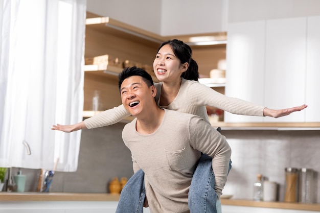 Alegre dama coreana que lleva a cuestas el alegre interior de la cocina de su esposo