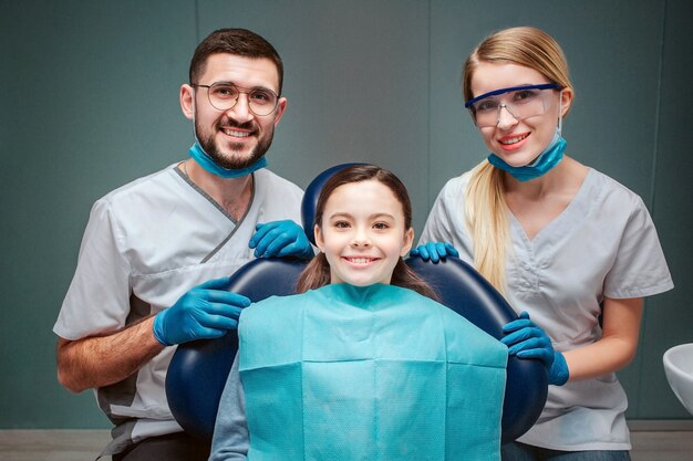 Alegre dentista masculino y femenino con niña.