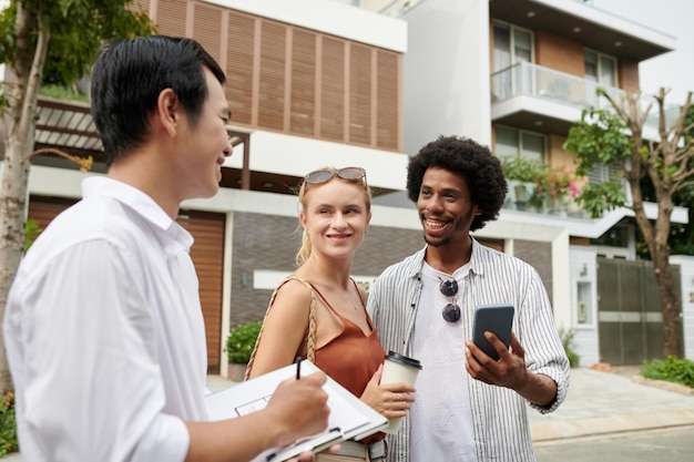 Una alegre y diversa pareja joven se reúne con un agente inmobiliario para encontrar una casa