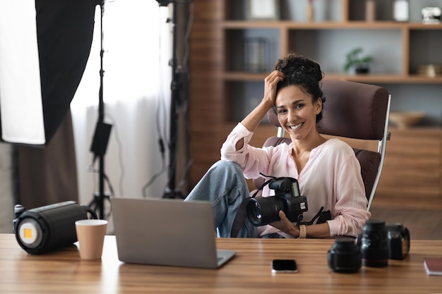 Alegre e bonita jovem fotógrafa profissional no local de trabalho