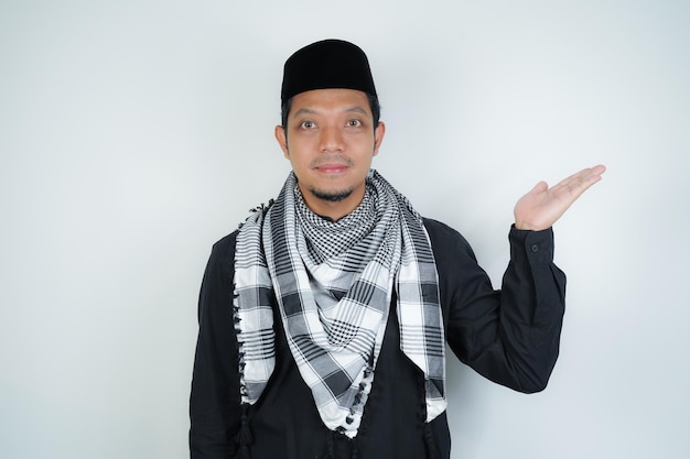 Alegre e bonito homem muçulmano asiático vestindo turbante árabe sorban apontando dedo da mão