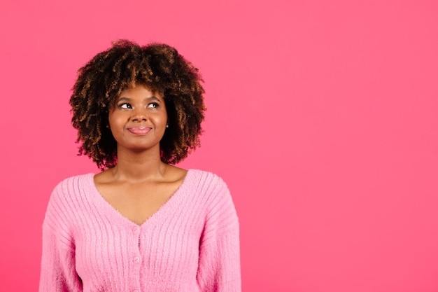 Alegre e confiante mulher afro-americana encaracolada em casual olhando para o espaço da cópia