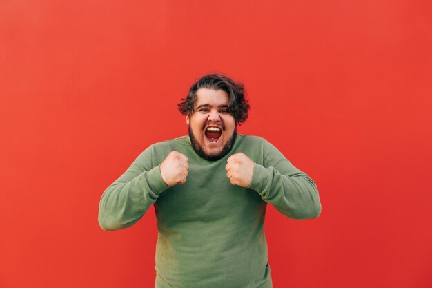 Foto alegre e feliz jovem hispânico barbudo está comemorando seu sucesso e conquista gritando