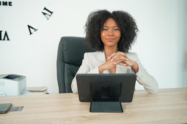 Foto alegre e relaxada jovem empresária afro usando laptop no trabalho