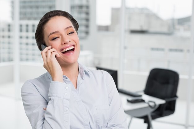 Alegre elegante empresaria usando teléfono celular en la oficina