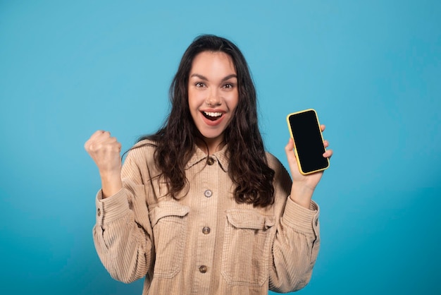 Alegre emocionada milenaria estudiante europea mostrar teléfono con pantalla vacía celebrar ganar