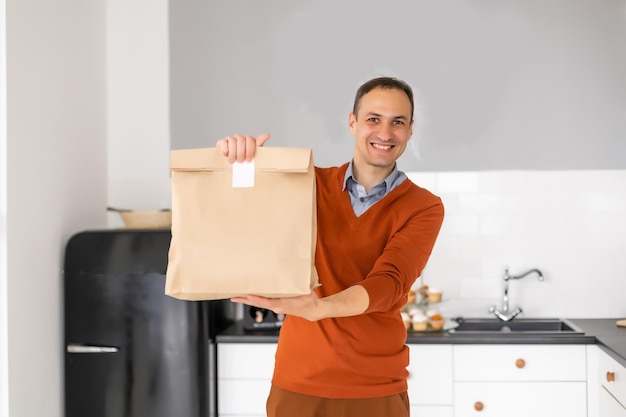 Alegre entregador. Correio jovem feliz segurando um pacote de entrega.