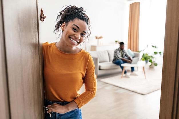 Foto alegre esposa negra conhecendo você sorrindo em pé no novo apartamento