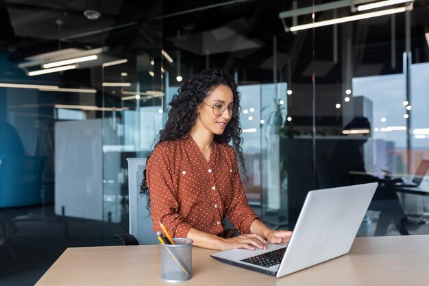 Foto alegre y exitosa programadora india en el trabajo dentro de la moderna trabajadora de soporte técnico de oficina