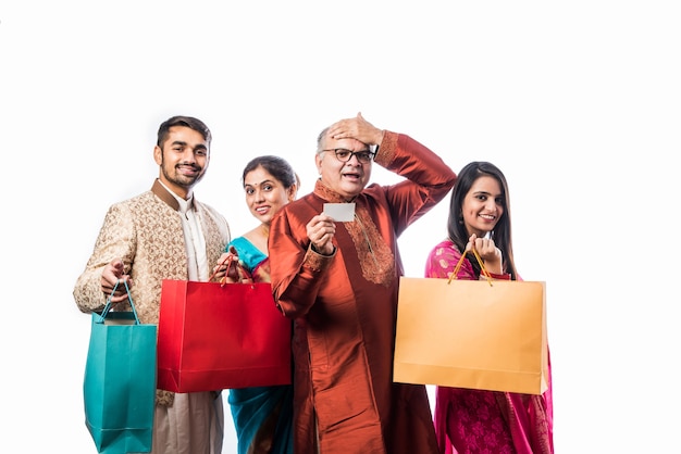 Alegre familia india de compras para el festival de Diwali o una boda, mostrando bolsas de papel de colores, aislado en blanco