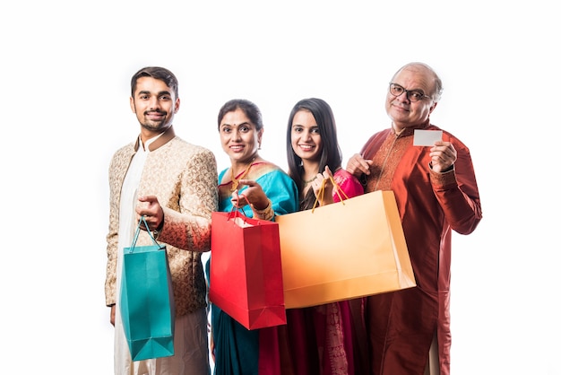 Alegre familia india de compras para el festival de Diwali o una boda, mostrando bolsas de papel de colores, aislado en blanco