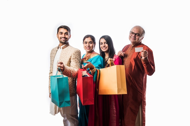 Alegre familia india de compras para el festival de Diwali o una boda, mostrando bolsas de papel de colores, aislado en blanco