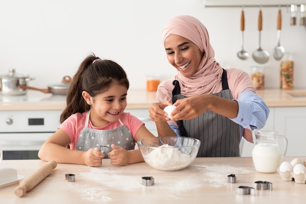 Alegre família muçulmana mãe e filha cozinhando juntos na cozinha