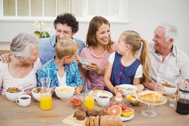 Alegre familia multigeneración desayunando