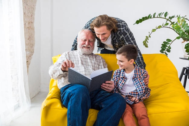 Foto alegre familia multigeneracional mirando a través del álbum de fotos.