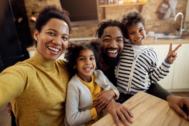 Alegre familia negra divirtiéndose mientras toma selfie en casa