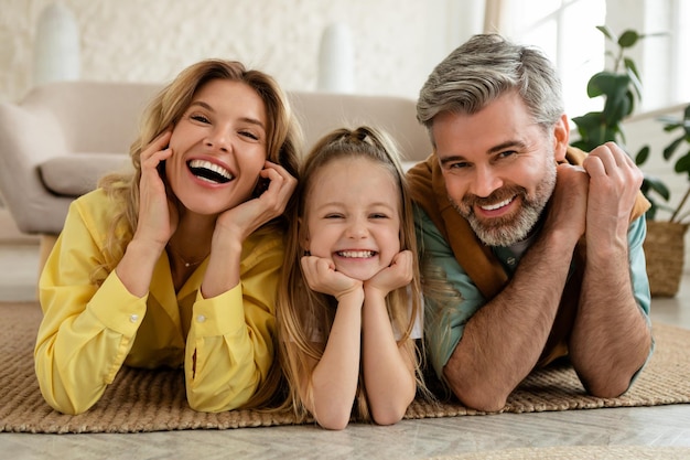 Alegre familia de tres posando sonriendo a la cámara en casa