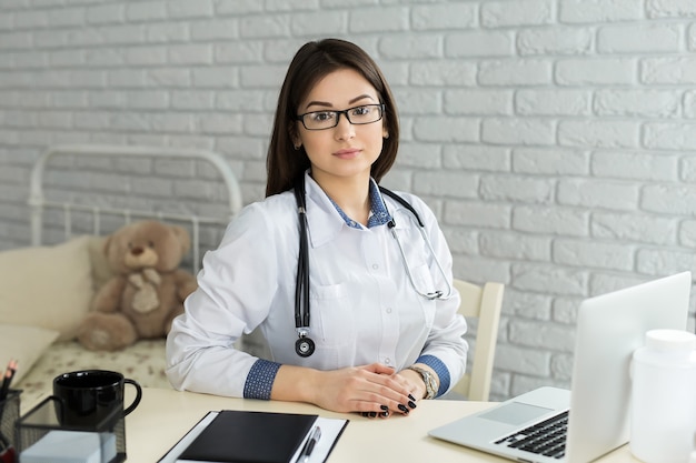 alegre feliz doctora sentada en su lugar de trabajo