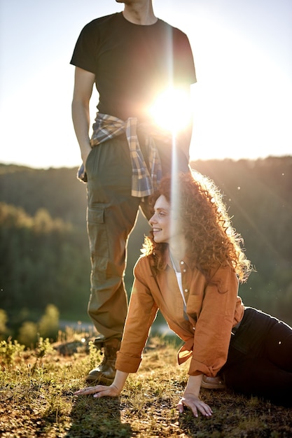 Alegre feliz joven pareja caucásica tomando un descanso durante la aventura en el campo pelirroja rizada fem ...