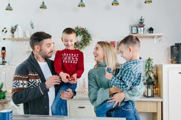 Alegre feliz matrimonio con dos hijos agitando las manos riendo divirtiéndose en casa para Navidad posando para cámara interior tecnología moderna Felicitaciones de año nuevo a familiares o amigos.