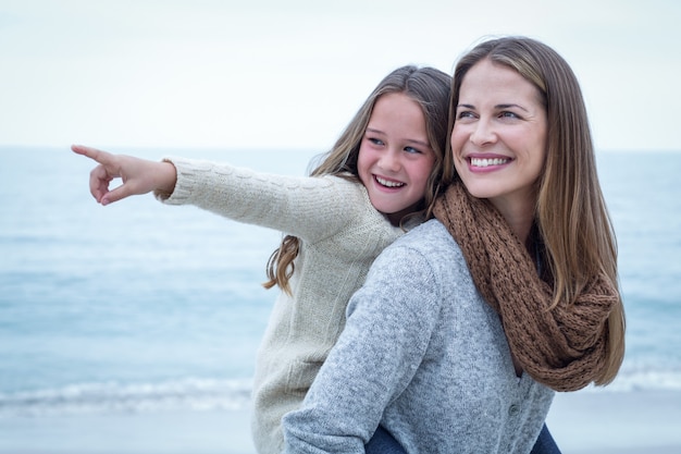 Alegre filha apontando enquanto mãe carregando ela