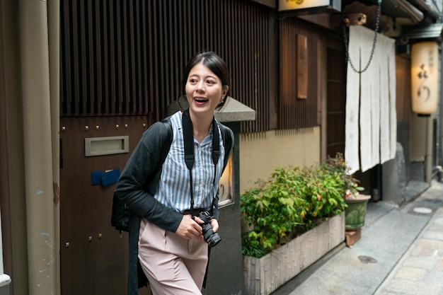 alegre fotógrafa asiática apreciando a bela paisagem do beco tradicional enquanto explora em um bairro antigo perto de nanba-eki Osaka japão.