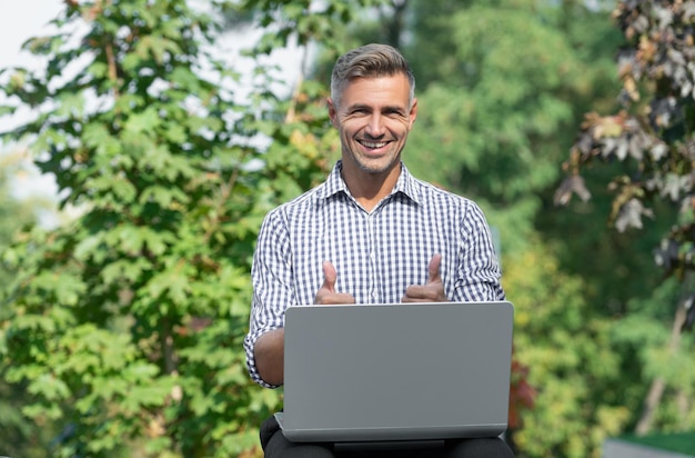 Alegre freelancer trabajando en laptop hombre freelancer al aire libre freelancer de negocios con pc