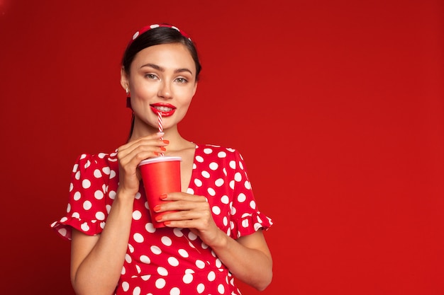 Alegre garota pin-up morena segurando refrigerante