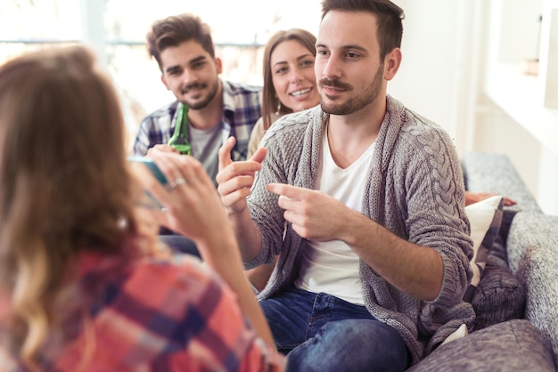 Alegre grupo de amigos divirtiéndose en casa, jugando a la asociación.