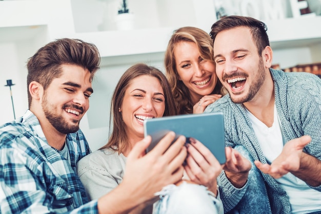 Alegre grupo de amigos divirtiéndose en casa, tomándose selfie.