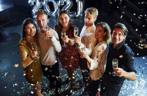 Alegre grupo de personas con bebidas en las manos celebrando el nuevo año 2021.