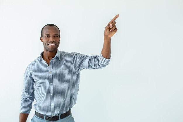 Alegre guapo afroamericano sonriendo mientras apunta a un lado