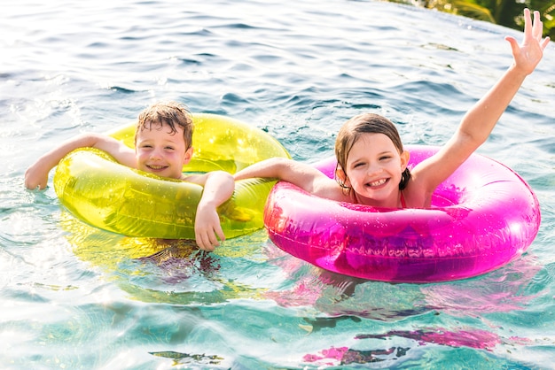 Alegre hermano y hermana nadando en la piscina